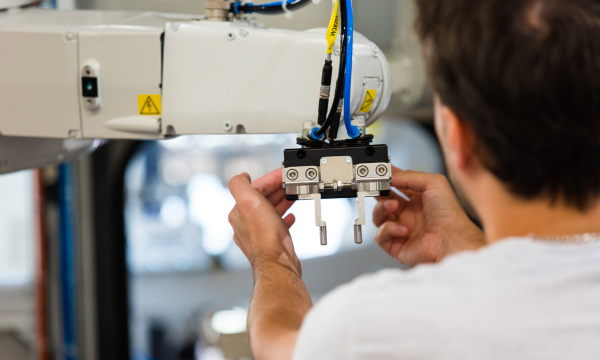 Human and robot collaboration in industrial automation Technician adjusting robot gripper for industrial automation system