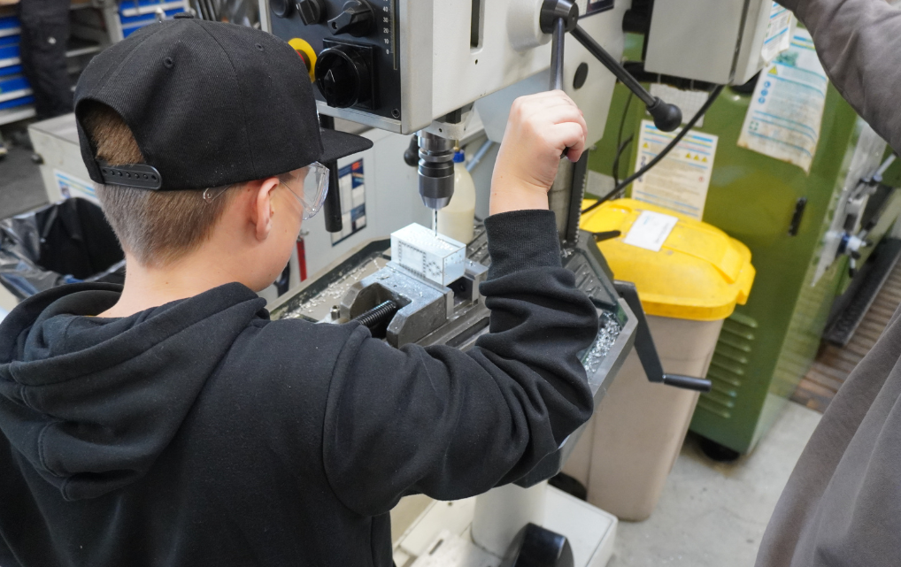 Kind arbeitet an einer Standbohrmaschine in der Werkstatt während des Kids Day bei esmo