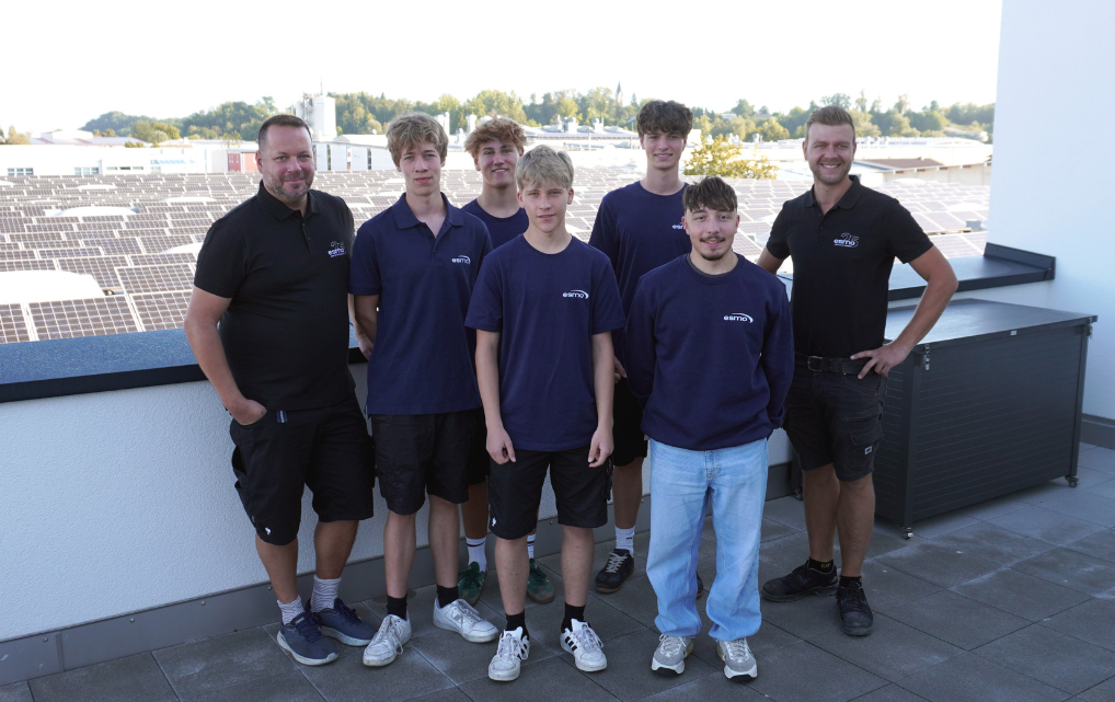 Five new esmo AG apprentices stand with two supervisors on a rooftop terrace in Rosenheim.