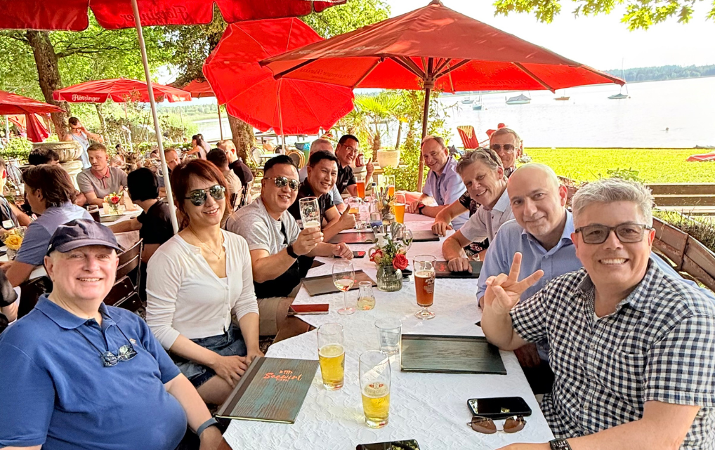 An international group of esmo colleagues having lunch together at a lakeside restaurant.