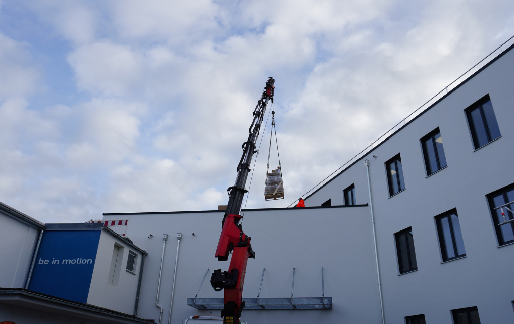 Kran hebt Baumaterial auf das Dach des neuen esmo Gebäudes