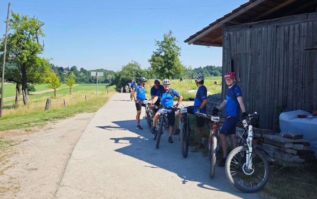  Teilnehmende der esmo Gravel-Gruppe beim Zwischenstopp neben einer Holzhütte